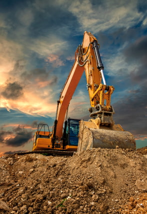 Excavator on a mound scooping dirt